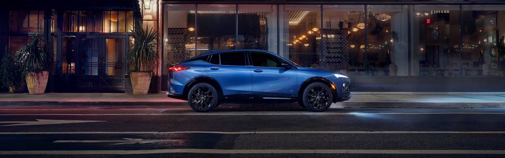 2026 Buick Envista Avenir compact SUV parked outside a modern city building at night.